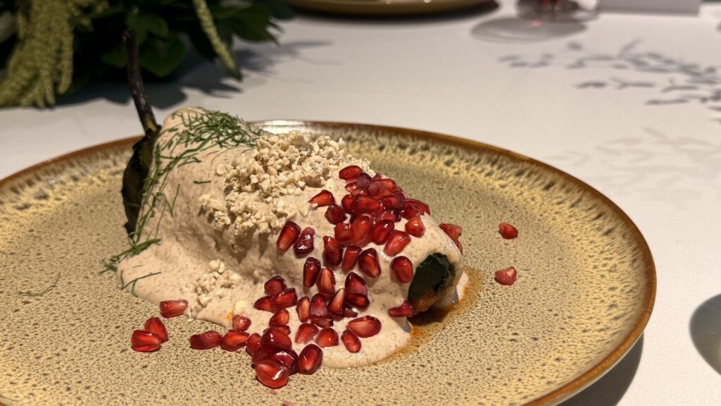 Chiles en nogada de Carolo en CDMX servido en un plato, bañado de nogada y coronado con granada.