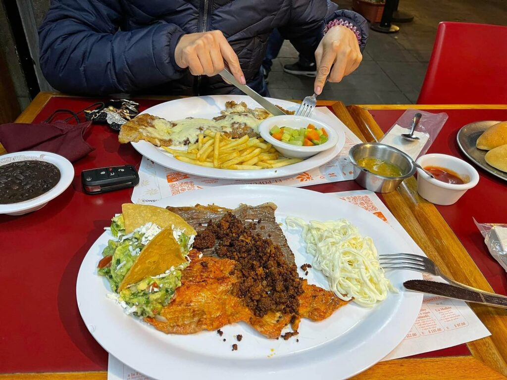 Platos con comida servida como una milanesa gratinada con papas a la francesa en Café El Popular, de los lugares abiertos 24 horas en CDMX.