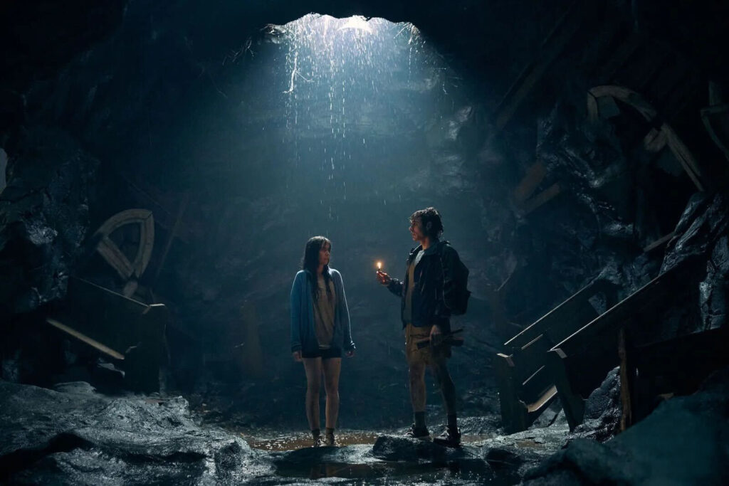 Escena de Together: juntos hasta la muerte con los protagonistas bajo la lluvia en una cueva iluminada.