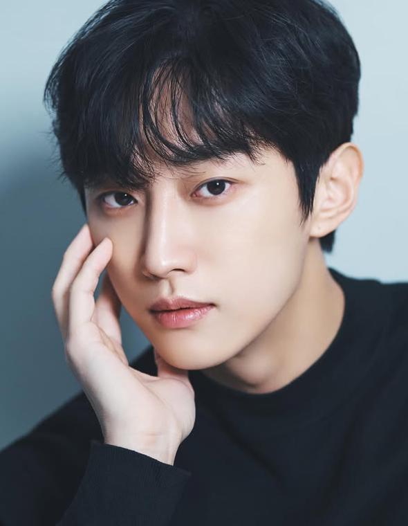 Retrato de Jin Young usando un suéter negro.