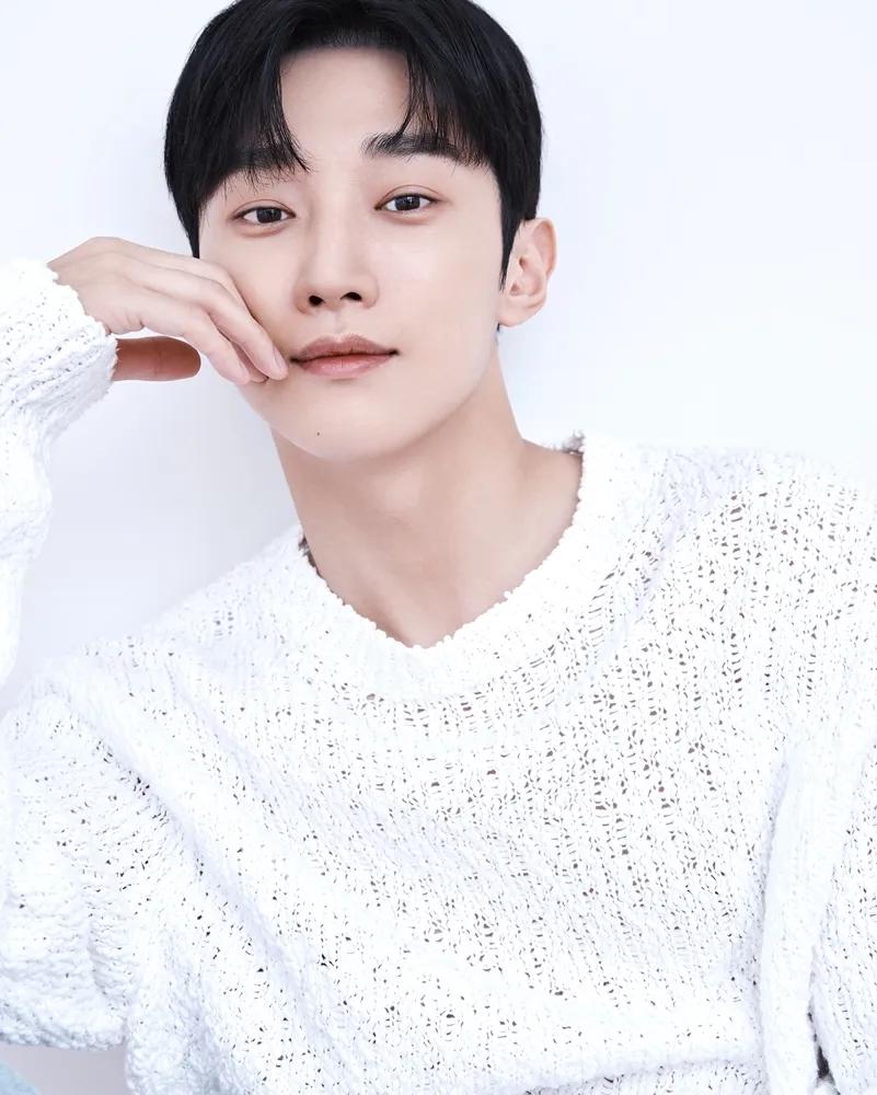 Retrato del actor Jin Young usando un suéter blanco.