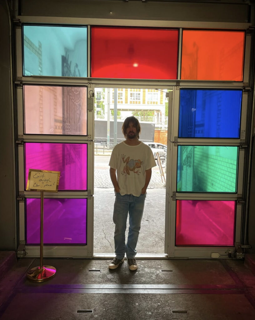 Retrato de Kevin Parker en una puerta con vitrales de colores.
