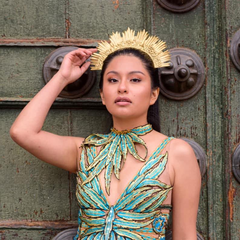 La cantante peruana usando un vestido verde agua y corona dorada.
