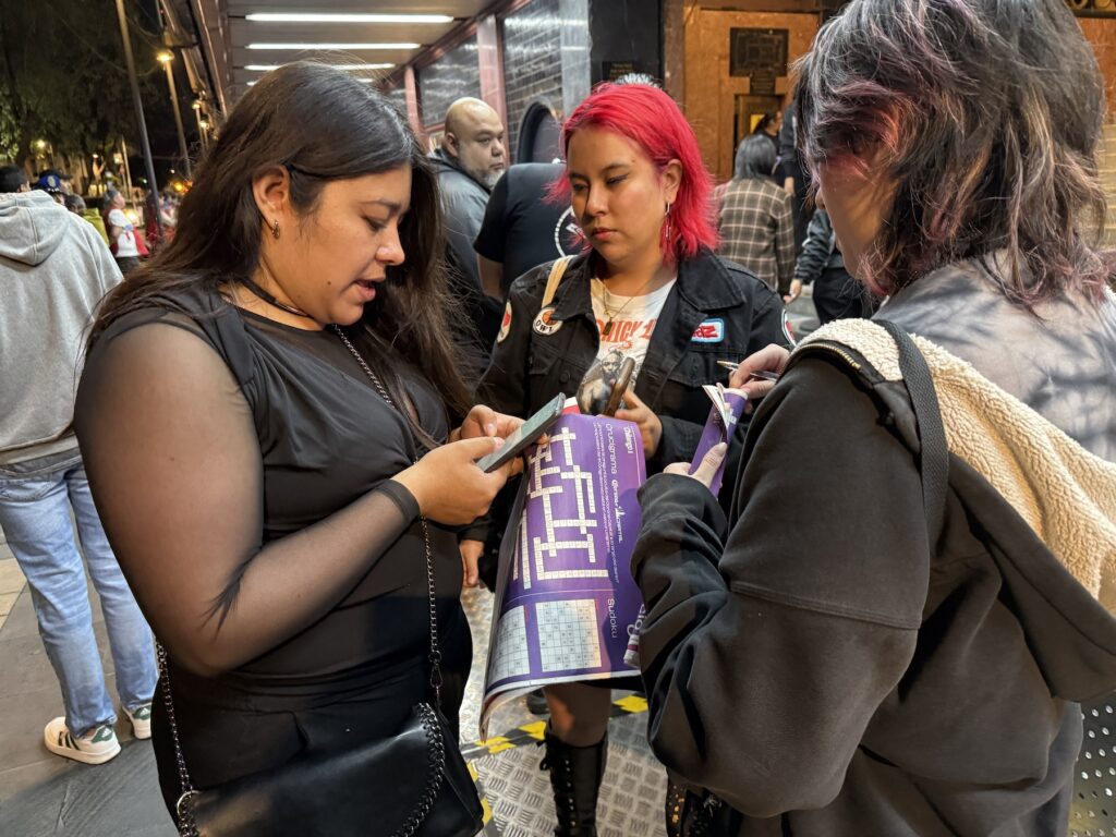 Participantes del Código Secreto afuera del Teatro Metropólitan resolviendo el crucigrama.