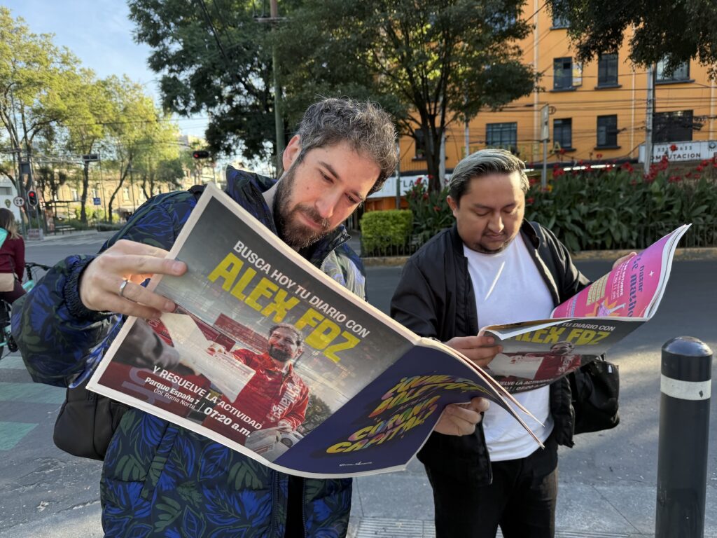 Alex Fernández y un participante del Código Secreto leyendo un Chilango Diario.
