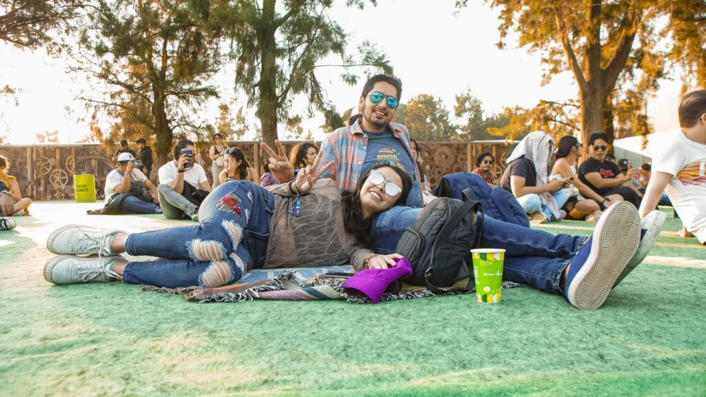 Pareja sentada en el pasto durante el festival corona capital.