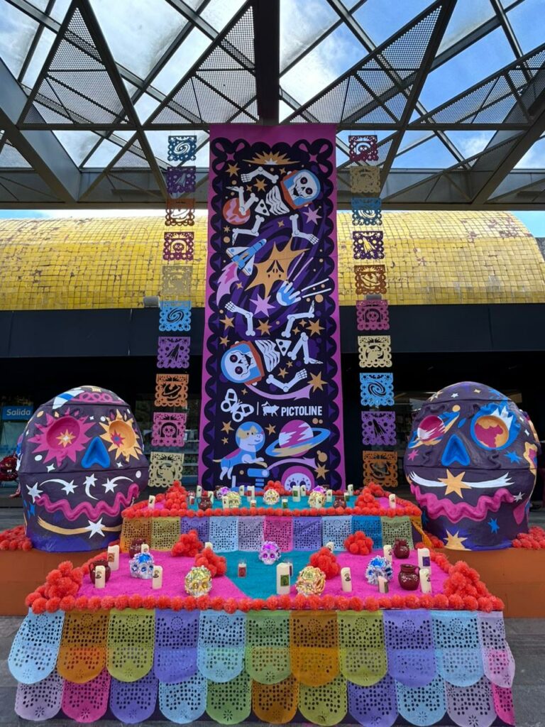 Altar con calaveritas de azúcar, velas y papel picado afuera del Papalote.