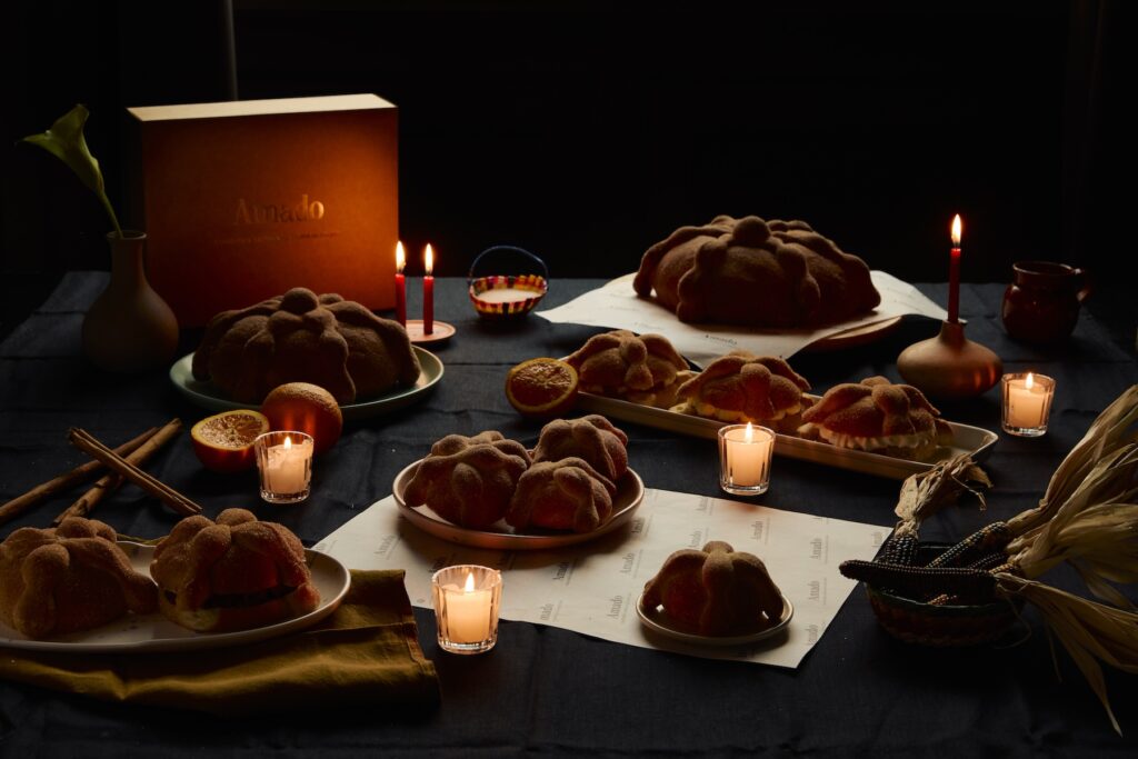 Pan de muerto de diferentes tamaños en una mesa con velas.