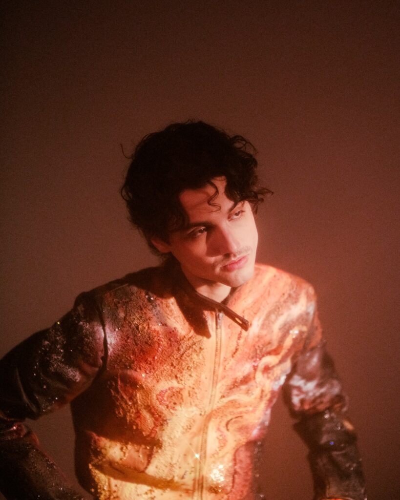 Retrato de Humbe usando una chamarra con estampado de galaxia.