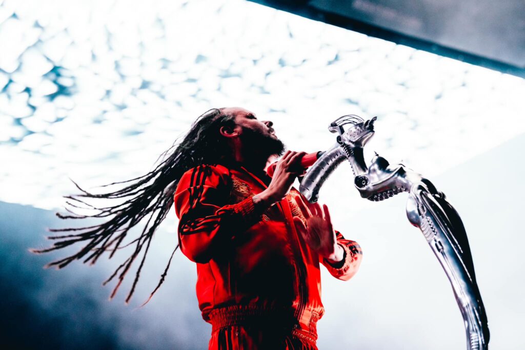 Jonathan Davis usando una chamarra roja y cantando en concierto.