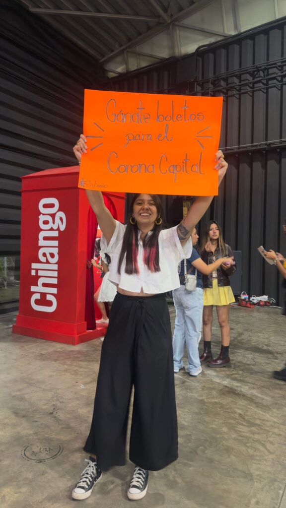 La Chío con una cartulina fosforescente afuera de La Cabina Roja en el Palacio de los Deportes.
