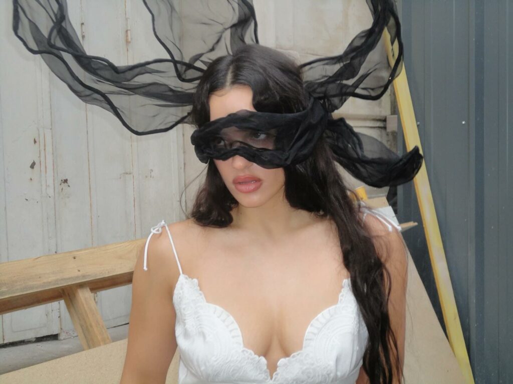 Retrato de Rosalía usando un vestido blanco y un antifaz negro.
