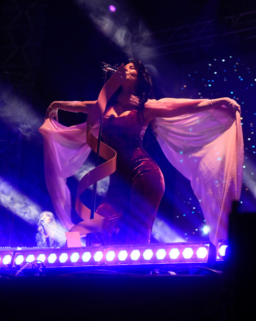 Marina cantando usando un body rosa.