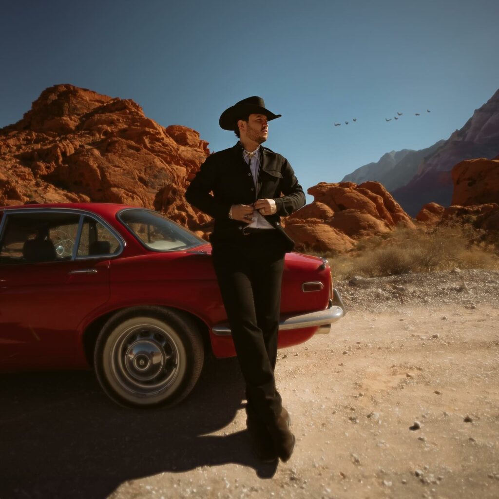 Edén Muñoz recargado en un auto rojo.