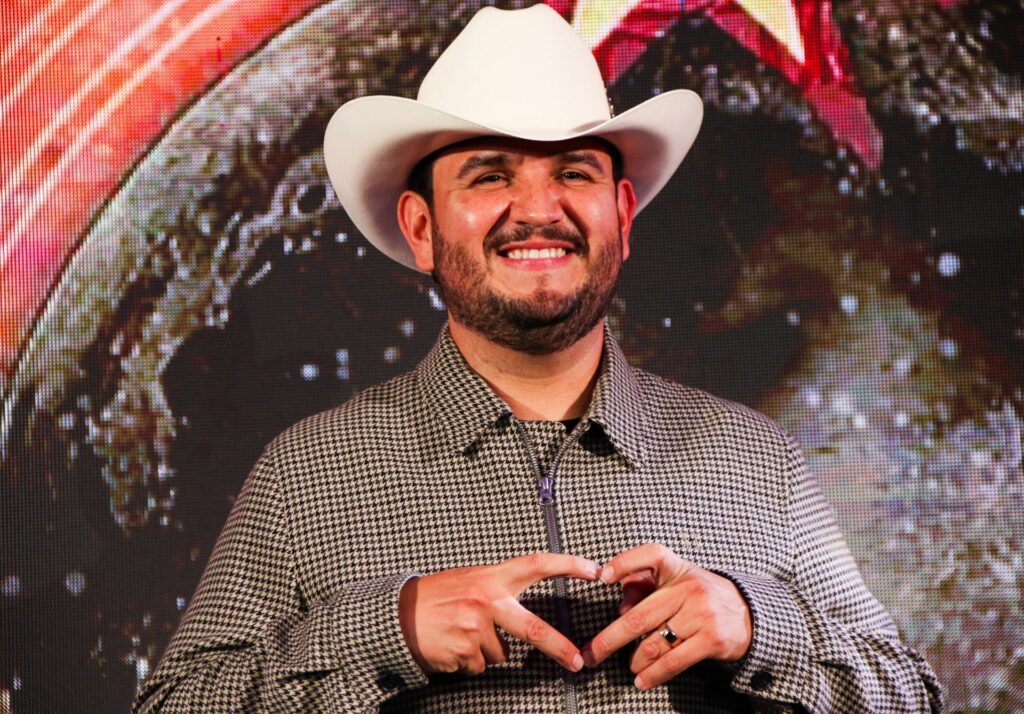 Edén riendo y haciendo un corazón con las manos.