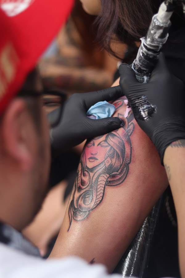 Artista haciendo un tatuaje en una pierna.