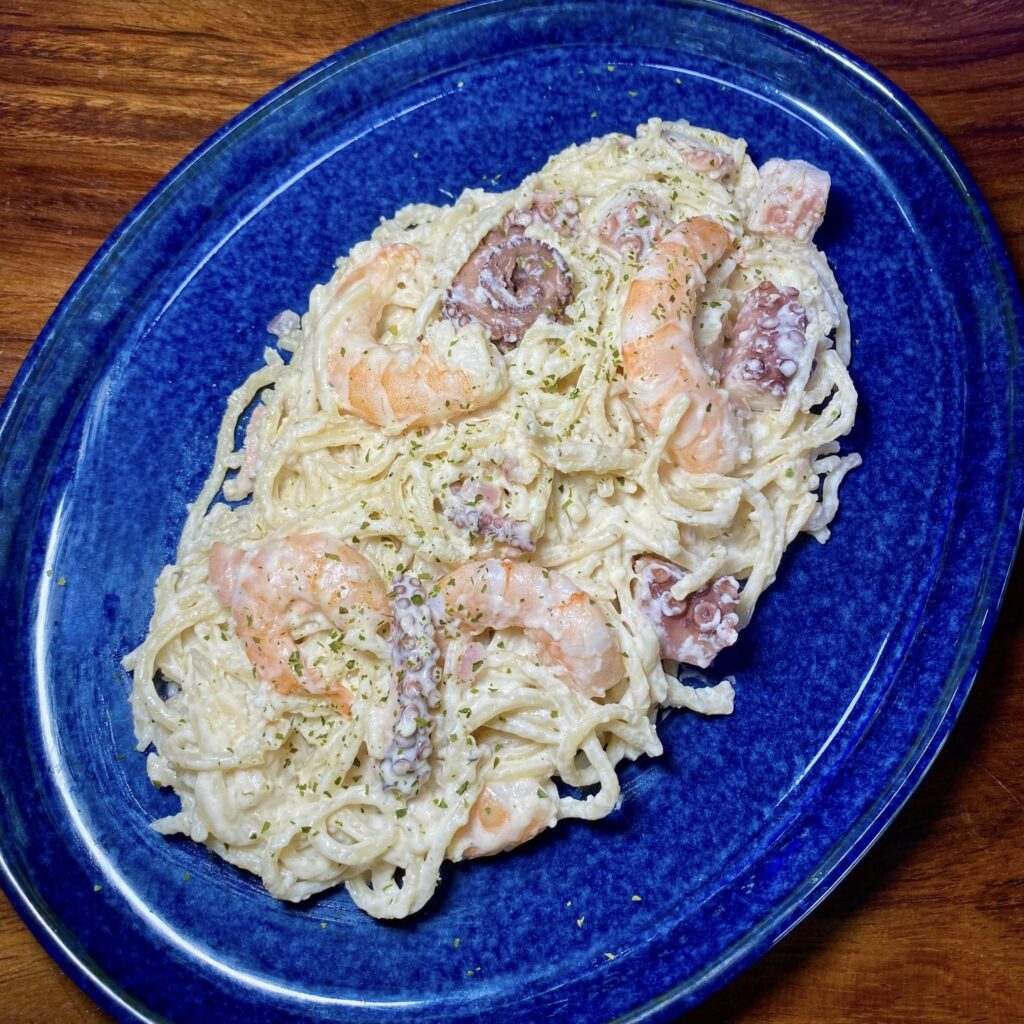 Pasta cremosa con camarones y pulpo troceado.