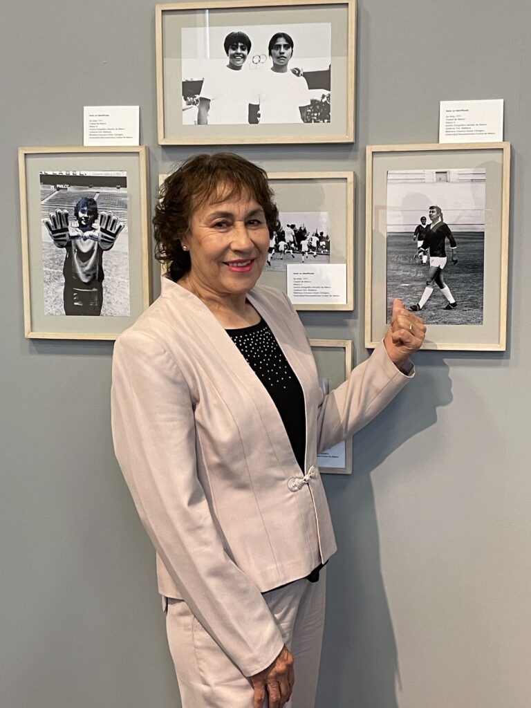 Alicia Vargas posando frente a fotos del Mundial Femenil de 1971, celebrado en México