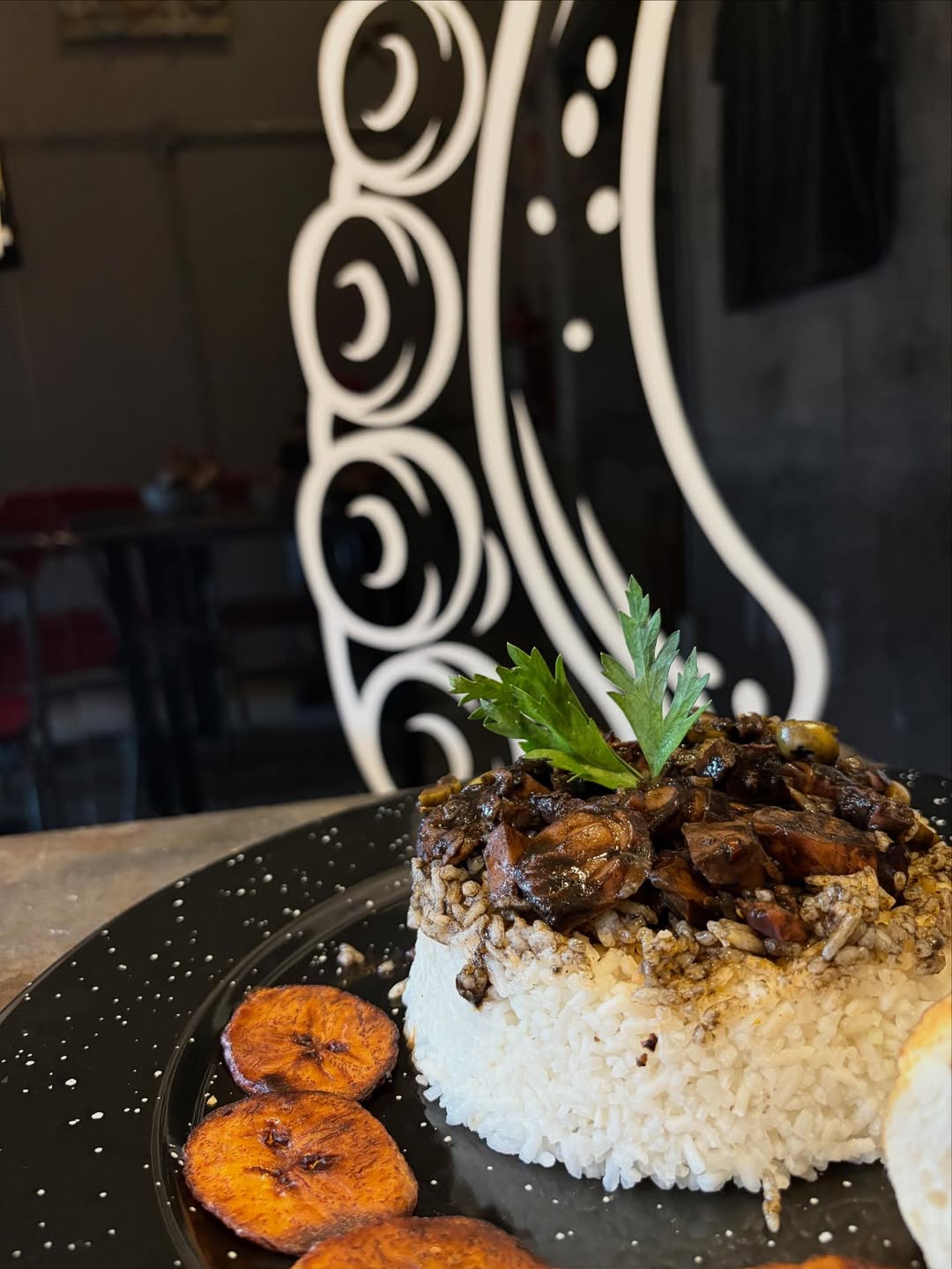 Timbal de arroz coronado con mariscos en su tinta y plátanos machos fritos.