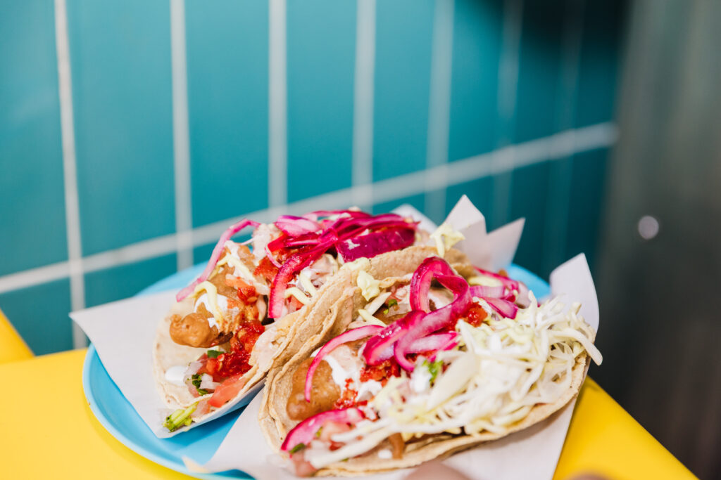 Dos deliciosos tacos de Don Sireno con carne asada, cebolla roja curtida y repollo rallado. 