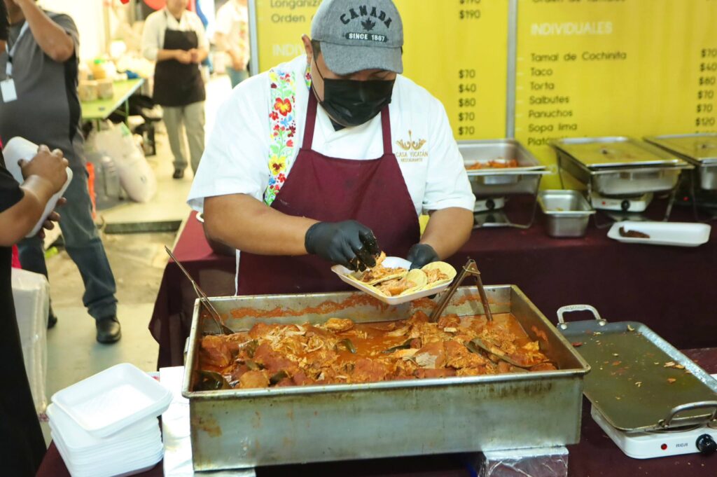 Cocinero de Casa Yucatán sirviendo tacos de cochinita pibil.
