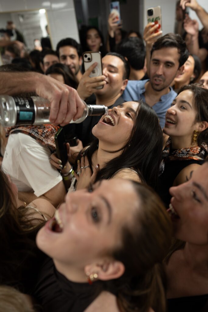 mujer tomando un shot en medio de personas