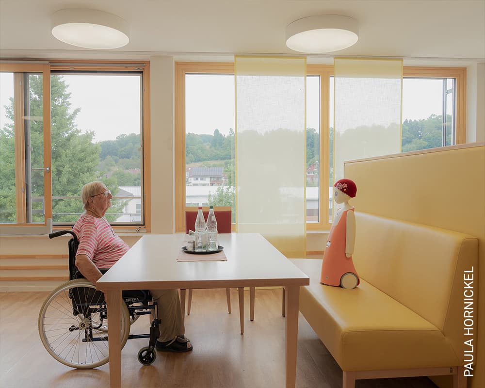Waltraud conversa con Emma, un robot social diseñado para reconocer rostros y recordar conversaciones previas. En Alemania, estas tecnologías comienzan a utilizarse como una herramienta para combatir la soledad entre adultos mayores. Foto: Paula Hornickel