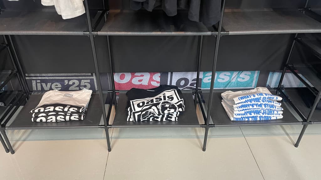 Playeras con prints de Oasis dobladas en una anaquel.