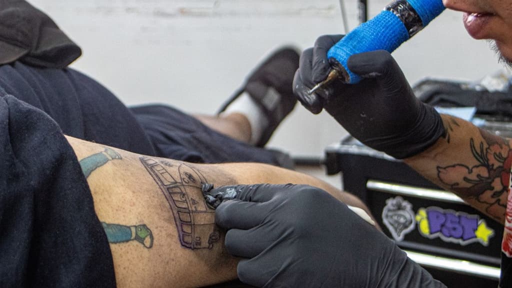 Artista tatuando a ganador de la dinámica Boletos x Tatuajes de Chilango y el Corona Capital.