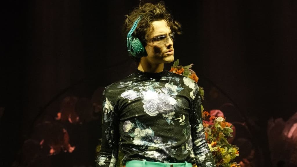 Humbe usando audifonos y una camisa mesh con estampado de flores.