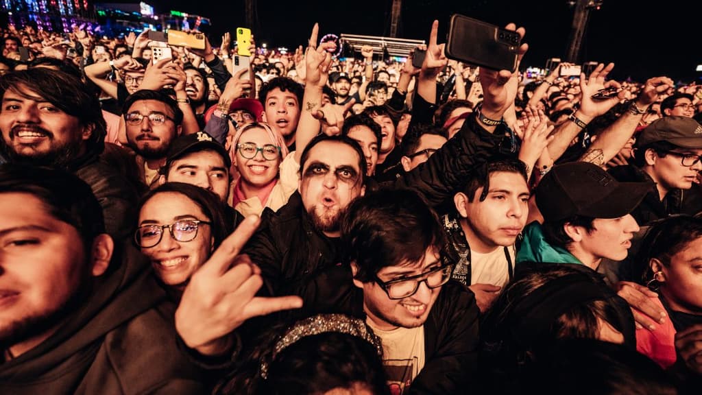 Asistente al festival Corona Capital gritando y haciendo la señal de rock con las manos.