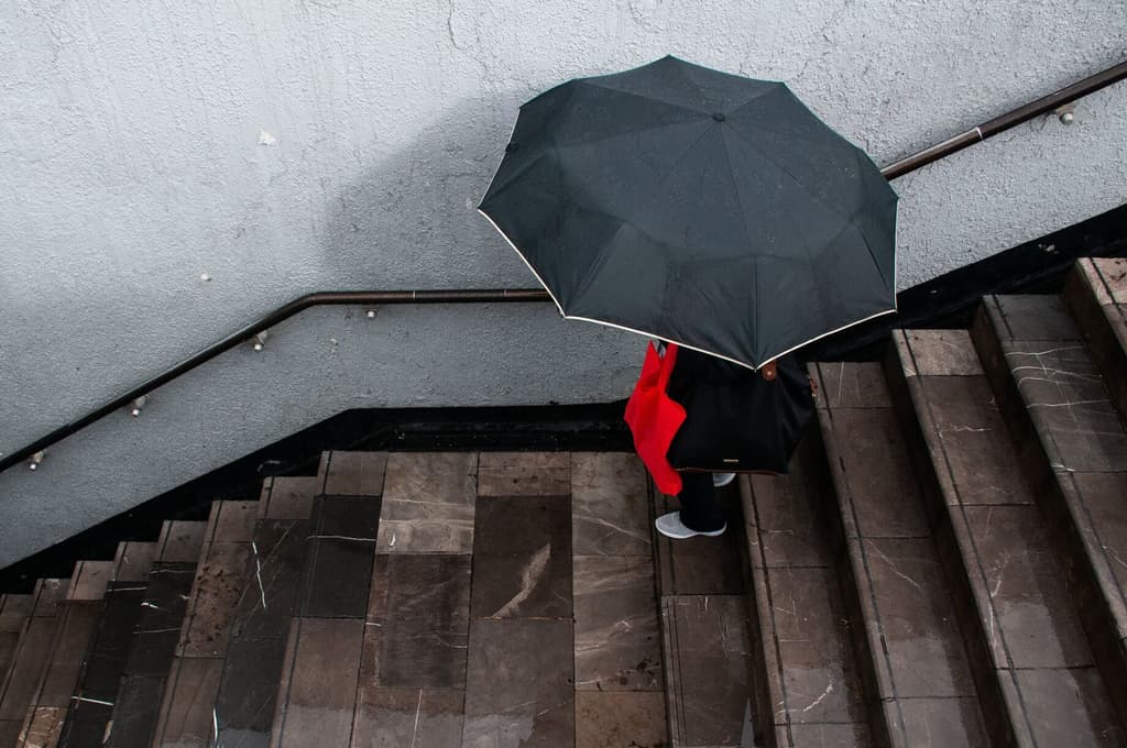 Una mujer entra al metro Centro Médico protegiéndose de la lluvia con un paraguas. Foto: Cuartoscuro