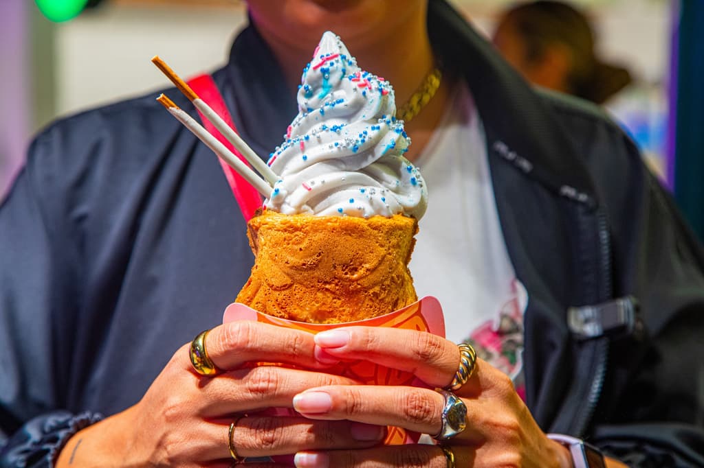 Mujer sosteniendo en las manos un taiyaki  con helado decorado con brillos. 