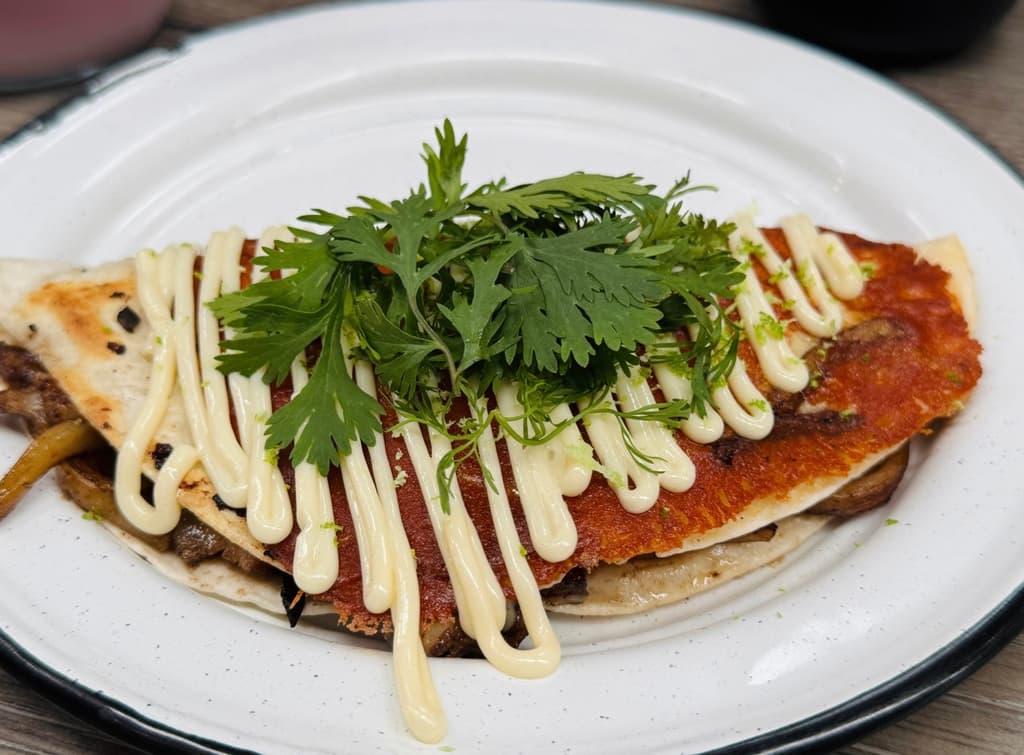 Okonomiyaki mexa: tortilla de harina con porck belly, costilla, fideo, udón, costra de queso, mayonesa, cilantro criollo y ralladura de limón.