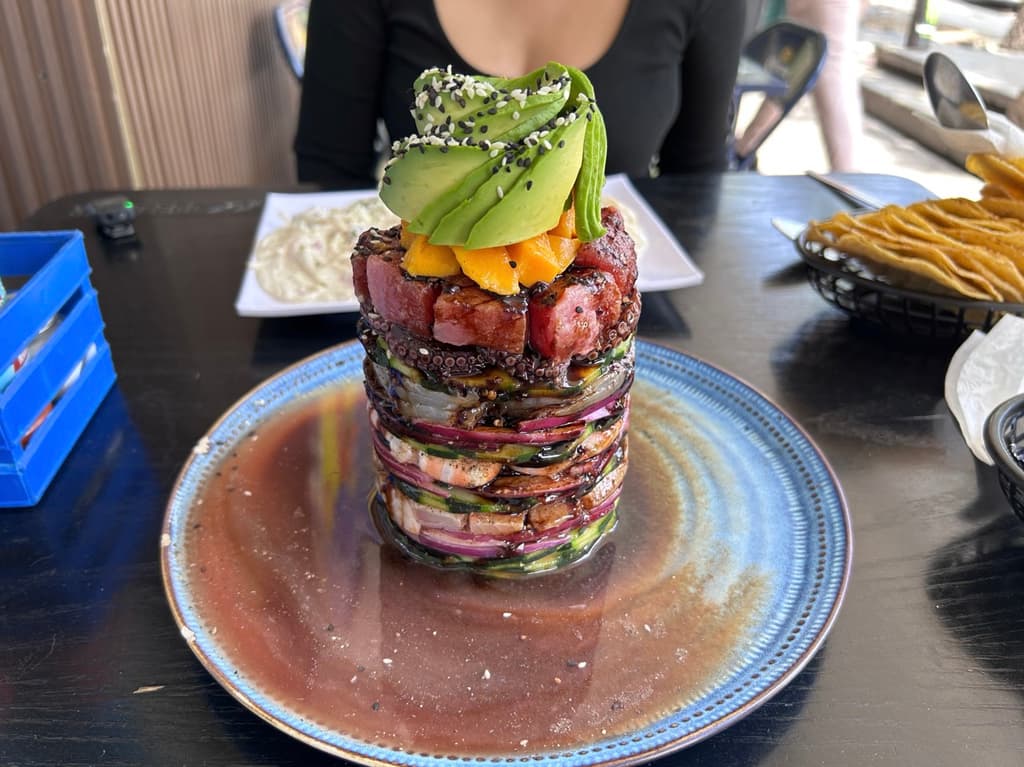 Torre de mariscos con camarón, pulpo y mango en salsa negra.
